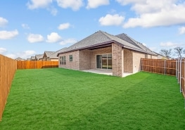A backyard with grass and a wooden fence.