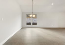 Empty living room with white walls and tile floors.