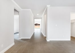 A hallway in a home with white walls and tile floors.