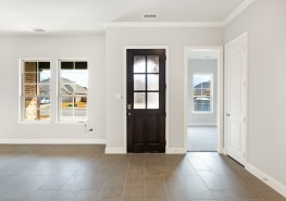 An empty room with a white door and tile floor.