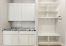 A white mudroom with a bench and cabinets.