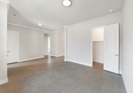Empty living room with tile floors and white walls.