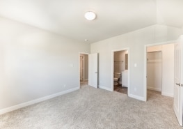 An empty bedroom with carpet and closets.