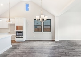 An empty kitchen with hardwood floors and a vaulted ceiling.