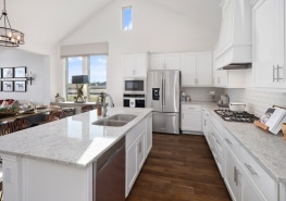 A white kitchen with a center island and stainless steel appliances.