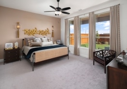 A bedroom with beige walls and a ceiling fan.