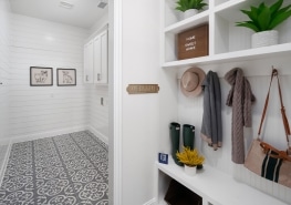 A white tiled mudroom with baskets and hats.