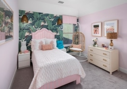 A pink and white bedroom with a tropical wallpaper.