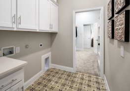 A laundry room with white cabinets and tiled floor.