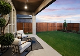 A backyard with a wooden fence and patio furniture.