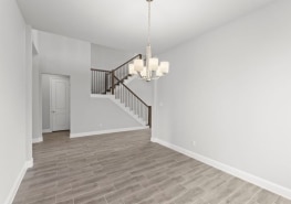 An empty room with hardwood floors and a staircase.