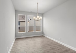 An empty room with hardwood floors and a chandelier.