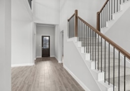 A staircase in a home with wood floors and white railings.