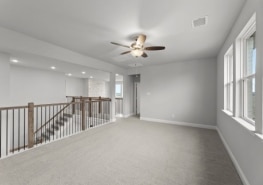 An empty room with a ceiling fan and stairs.