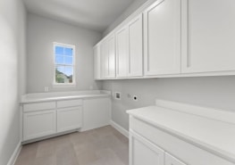 A white kitchen with white cabinets and a window.