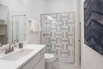 A white bathroom with a gray shower stall and sink.