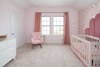 A pink and white baby room with a crib and a white dresser.