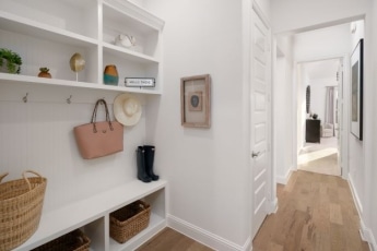 A white mudroom with baskets and a wooden floor.