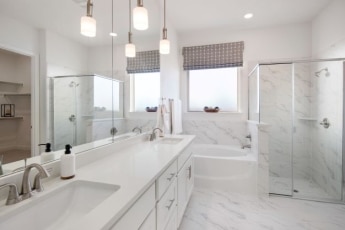 A white bathroom with two sinks and a walk in shower.
