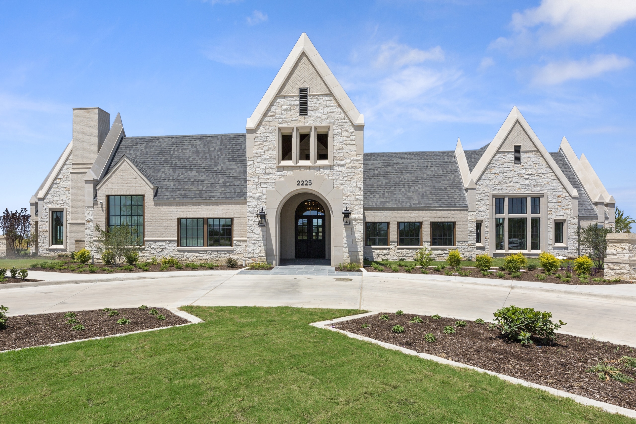 A large stone home with a large driveway.