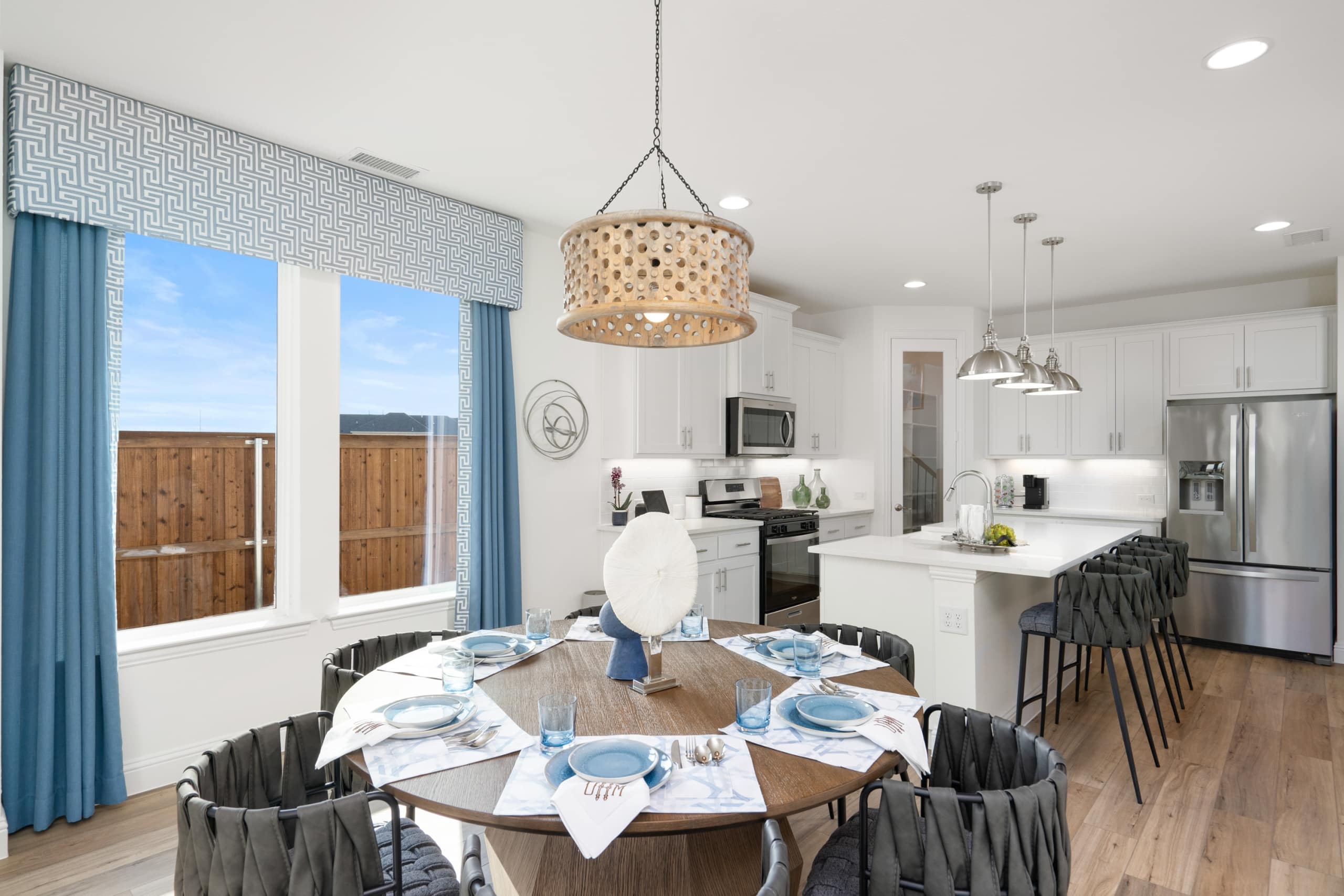 A kitchen and dining room with blue curtains, featuring a UnionMain Homes Promotion.