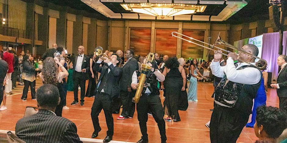 A group of people playing trumpets in a ballroom.