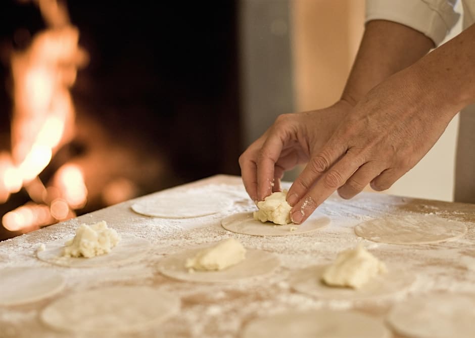 A person putting butter on a pastry dough in front of a fireplace.